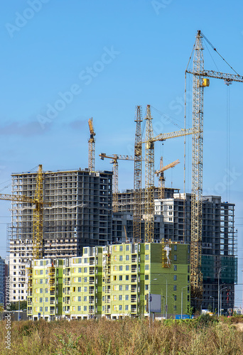 multistory buildings under construction made of reinforced concrete structures and frameworks with the help of construction machinery and cranes photo