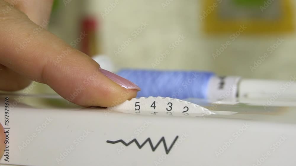 Adjusting the stitch width adjuster in the sewing machine.Close-up. Adjusting the stitch width adjuster in the sewing machine.Close-up.