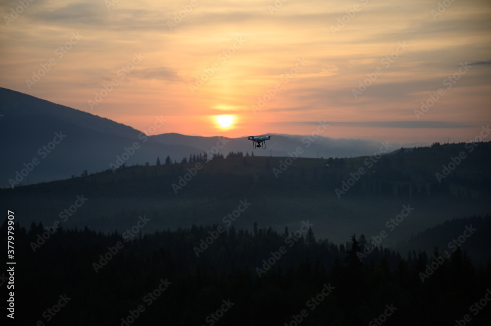 Silhouette Drone flying on mountain sunrise sky with cloud, Aerial photography. mountains landscape with sun and alpine pines. Sunrise
