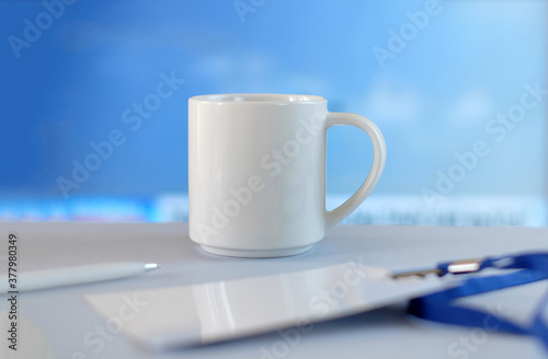White cup, badge and pen on white table soft blue background, business style © Olga Kazanovskaia 