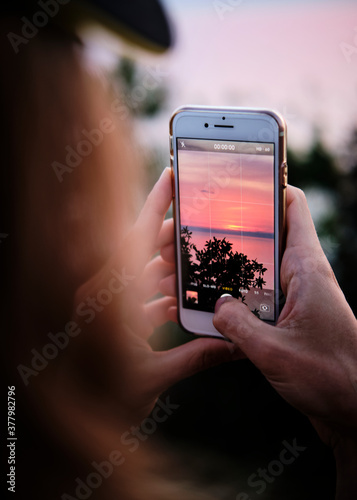 Foto scattata ad una ragazza che fotografa un tramonto.