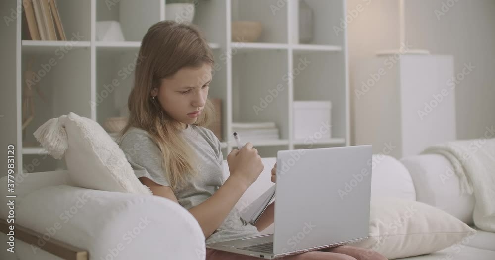 school girl is communicating with teacher by video chat on laptop, doing homework at home, distant education for secondary school school girl is communicating with teacher by video chat on laptop, doing homework at home, distant education for secondary school