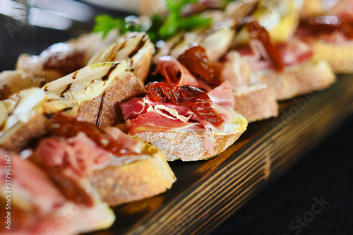 Set of bruschetta of 3 types with sun-dried tomato and ham, with brie cheese and pear, with turkey fillet with raspberry jam. Catering dishes, snacks