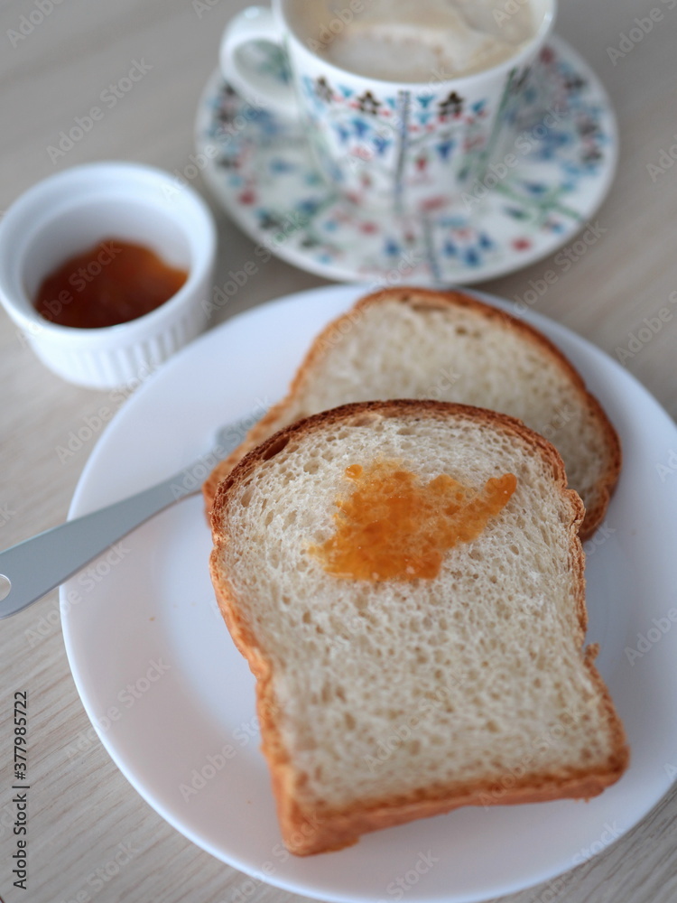 Homemade bread and apricot jam served with a cup of coffee latte with foam. A tasty and minimal refreshment in the afternoon. Homemade bread and apricot jam served with a cup of coffee latte with foam. A tasty and minimal refreshment in the afternoon.