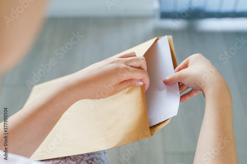 Close up on hands of unknown caucasian woman hold envelope opening or sending letter with mail or documents at home in day top view