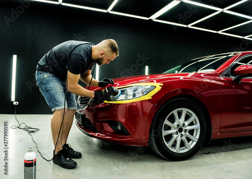 Car service worker polishes a car details with orbital polisher. © romaset