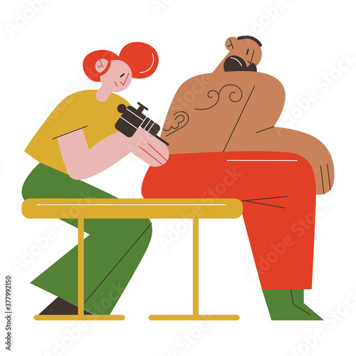 Woman tattoo master making tatoo on mans back in tattoo studio