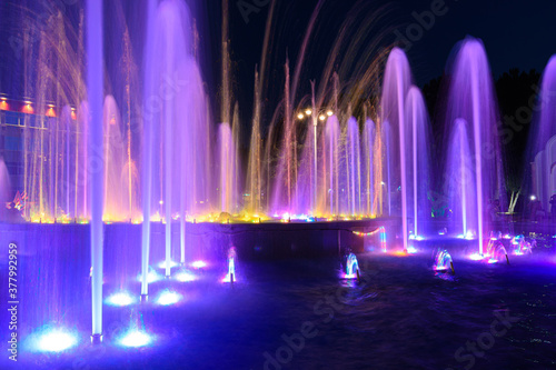 Jets of a night multi-colored illuminated fountain close-up