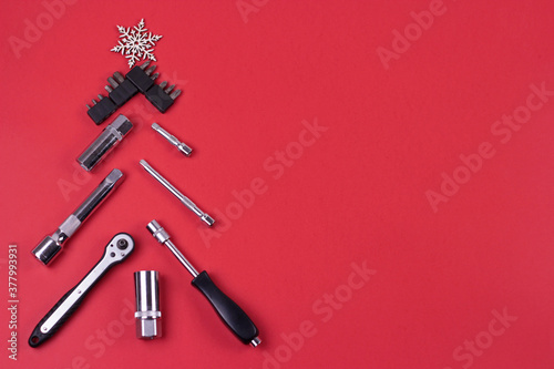 Creative christmas tree on red background, made of wrenches.Set of tools supplies for repair car on xmas backdrop. Industrial greeting card and christmas happy new year concept.