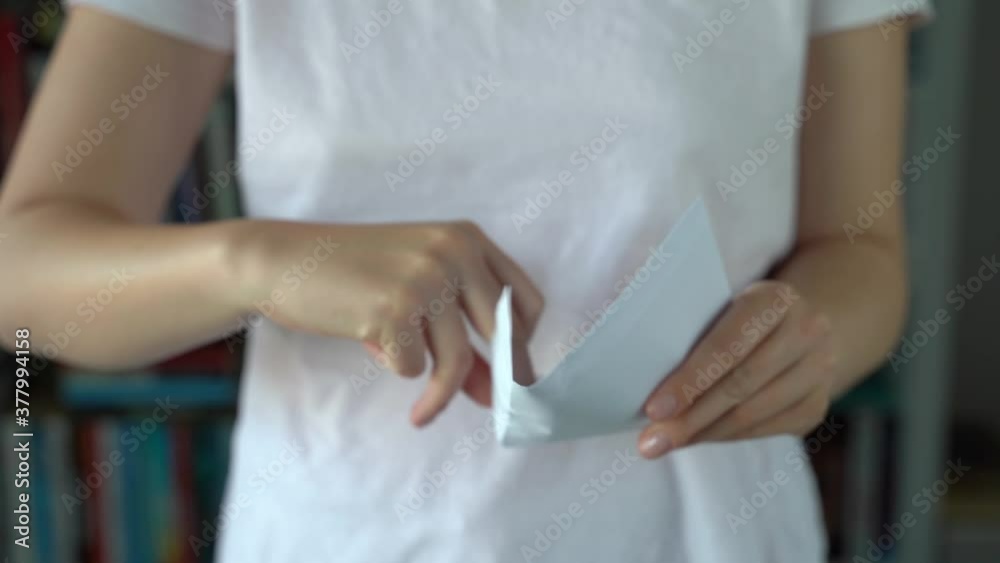 Front view close up on midsection of unknown caucasian woman holding an envelope at home in day - female hands opening letter Sending or receiving mail concept Front view close up on midsection of unknown caucasian woman holding an envelope at home in day - female hands opening letter Sending or receiving mail concept