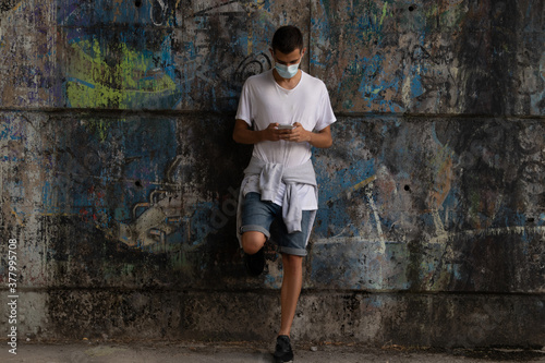 portrait of young man with mask and mobile phone