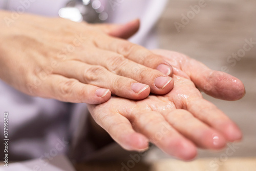 Fototapeta Naklejka Na Ścianę i Meble -  Closeup of a doctor's hands, in a white coat, disinfecting his hands with hand sanitizer. Medical and health care concept.