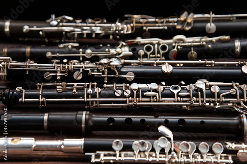 Many woodwind instruments lie on a wooden surface. View from above photo