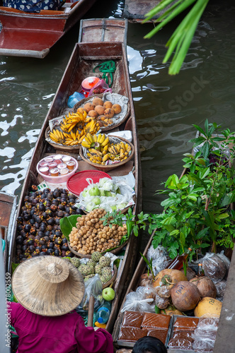 Woman in a small boat selling fruits and vegetables at a floating market in Thailand.