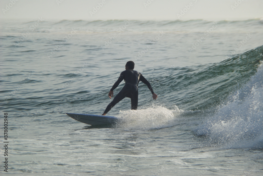Surfista a fazer surf numa onda no mar ao por do sol