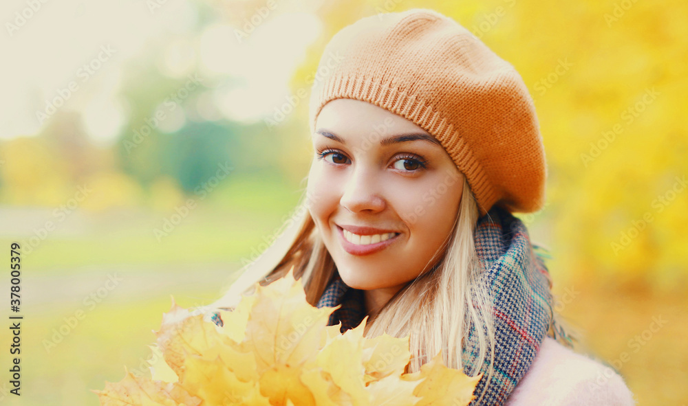 Portrait of beautiful smiling blonde woman with yellow maple leaves in autumn park wearing beret Portrait of beautiful smiling blonde woman with yellow maple leaves in autumn park wearing beret