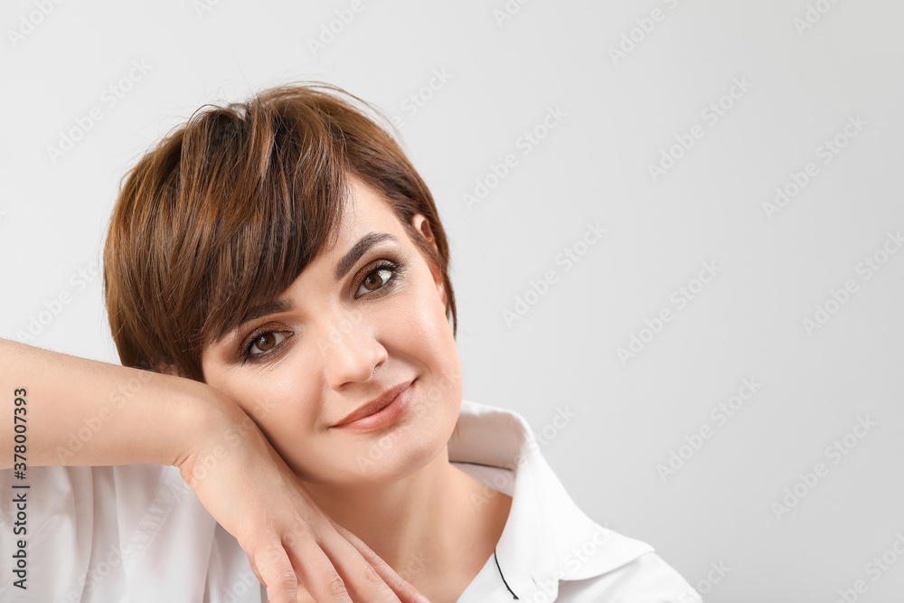 Young woman with beautiful short hair on grey background