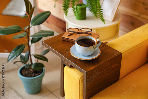 Φωτογραφία Cup of tea with book on armrest table in room