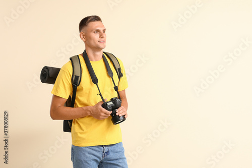 Male tourist with camera on color background