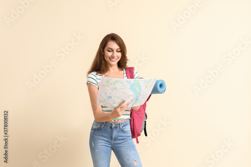 Female tourist with map on color background