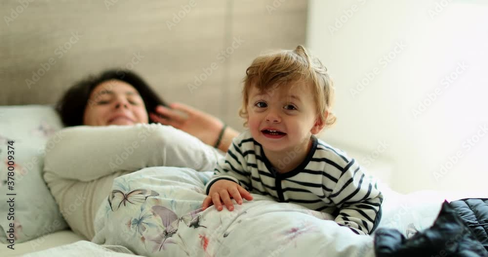 Sweet baby smiling at camera in morning bed with mom Sweet baby smiling at camera in morning bed with mom