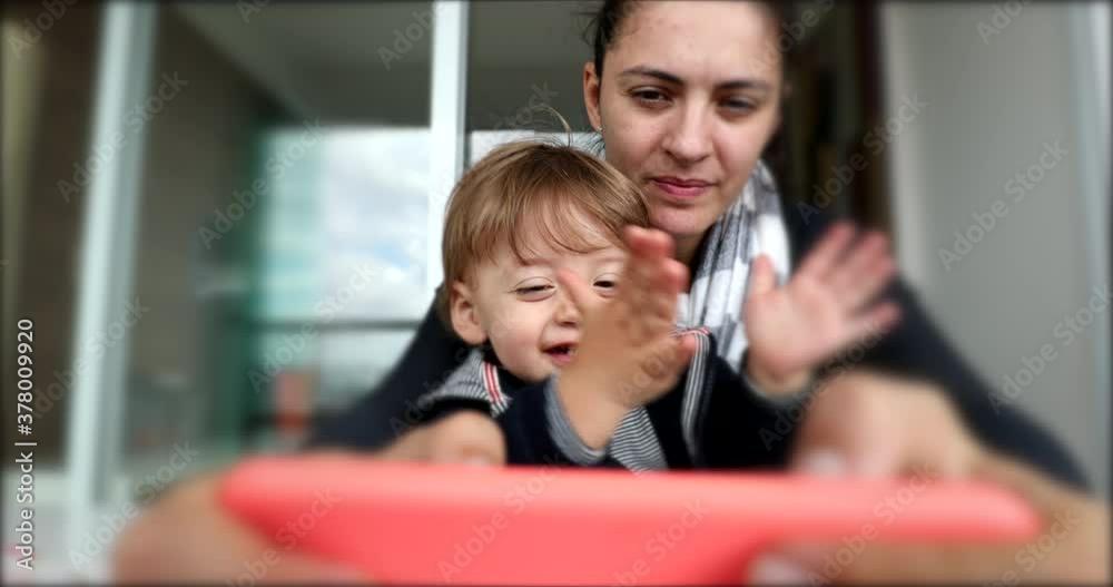 Toddler boy clapping hands while on mom lap watching smartphone screen Toddler boy clapping hands while on mom lap watching smartphone screen
