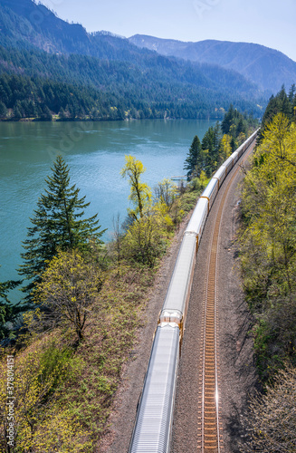 The train goes by rail road along the gorgeous Columbia River with mountains covered with forests at Columbia Gorge