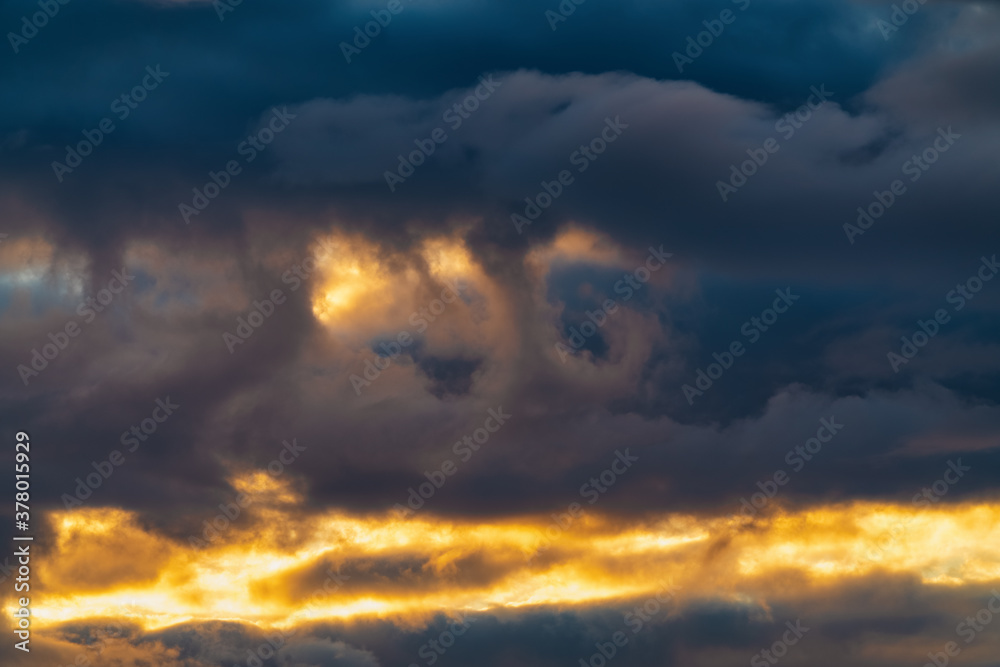 Impressive clouds in sky illuminated by rays of sun at sunset to change weather. Soft focus, defocus, motion blur multicolored cloudscape abstract meteorology background.