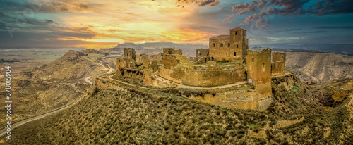 Dramatic aerial sunset view of Montearagon castle near Huesca Spain, with partially restored walls and towers on a bare hilltop photo