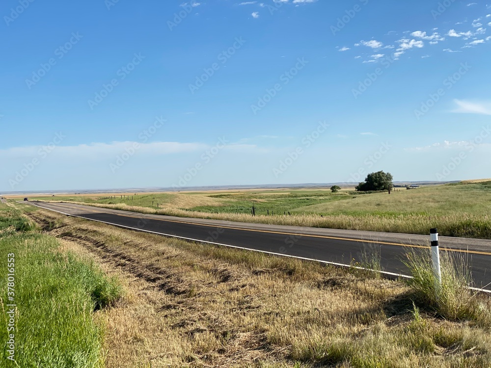 Highway cutting through prairie fields 