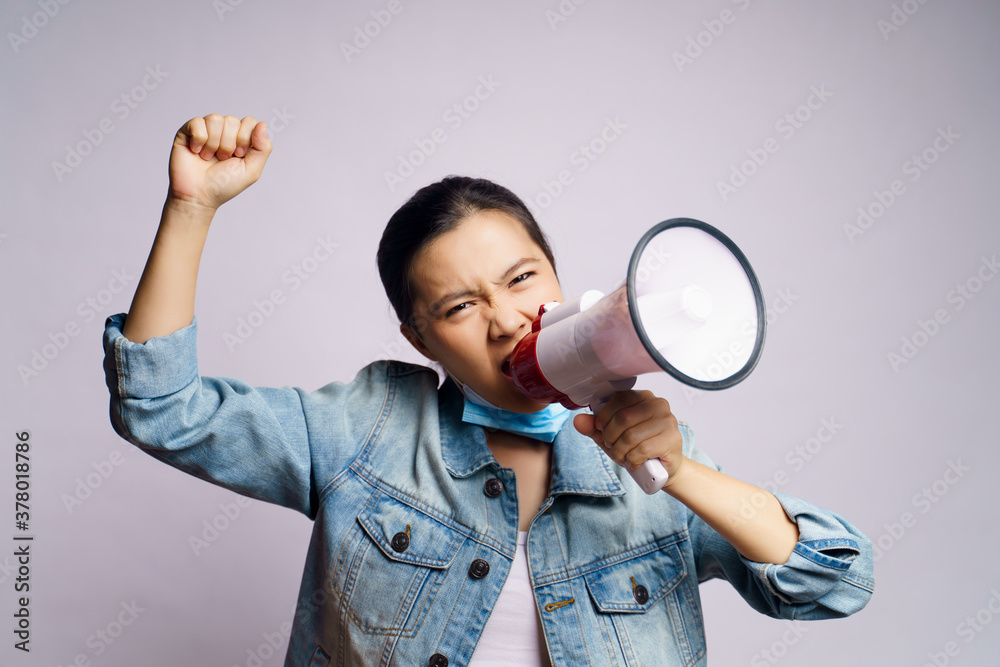 Asian woman wearing protective face mask shouting with megaphone isolated over white background. Asian woman wearing protective face mask shouting with megaphone isolated over white background.