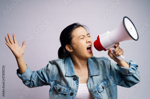 Asian woman shouting with megaphone isolated over white background.