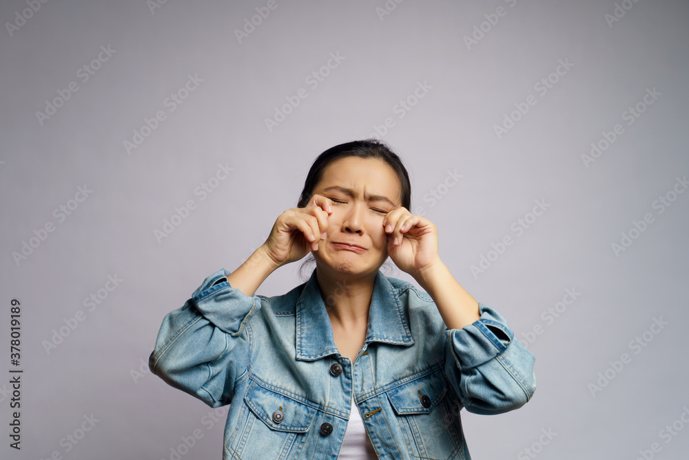 Asian woman sad and crying standing isolated over white background. Asian woman sad and crying standing isolated over white background.