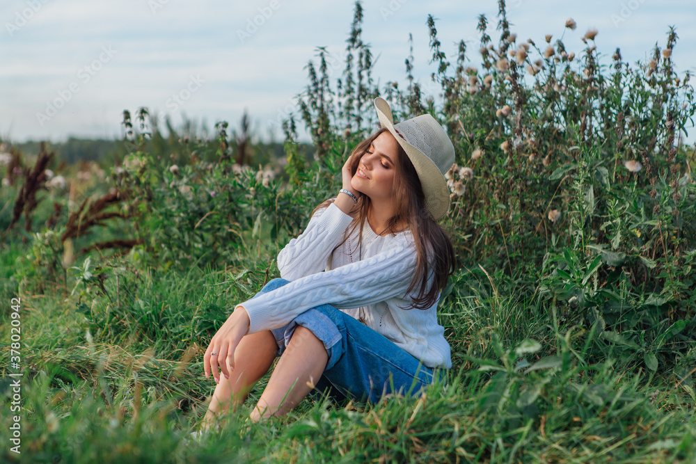 Young beautiful brunette woman sitting on the grass and smiling Young beautiful brunette woman sitting on the grass and smiling