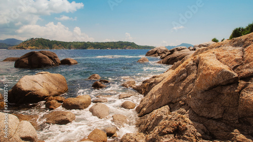 Landscape with sea waves crashing over rocks the sea and the beautiful clouds in the blue sky.