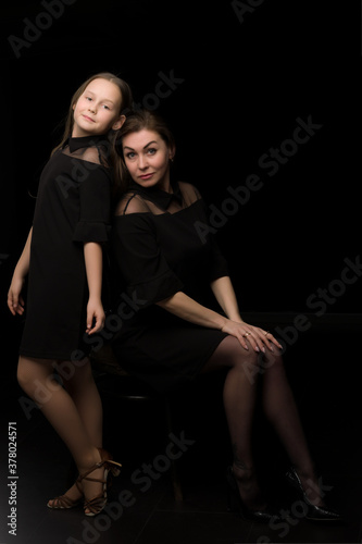 Mom and daughter in the studio on a black background.