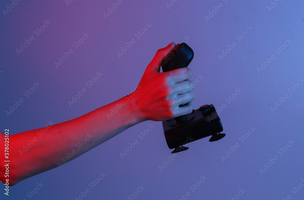 Hands holding retro joystick in blue-red neon gradient light. Old gaming. 80s retro wave Hands holding retro joystick in blue-red neon gradient light. Old gaming. 80s retro wave