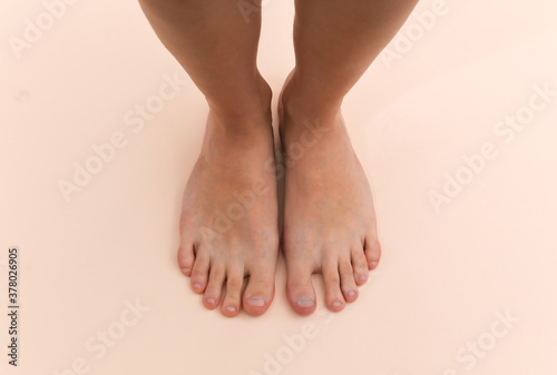Fototapeta Naklejka Na Ścianę i Meble -  Female bare feet on a beige background. Beauty Care Concept