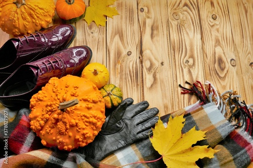 Fashionable autumn accessories and shoes.Fall fashion.Autumn discounts and sales. scarf, leather gloves set, leather patent leather shoes, pumpkins and maple leaves on a wooden background