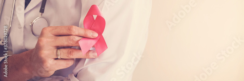 Doctor holding pink ribbon, breast cancer awareness, October pink concept