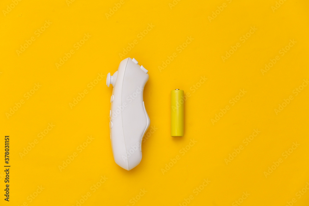 Wireless joystick and two batteries on yellow background. Top view Wireless joystick and two batteries on yellow background. Top view