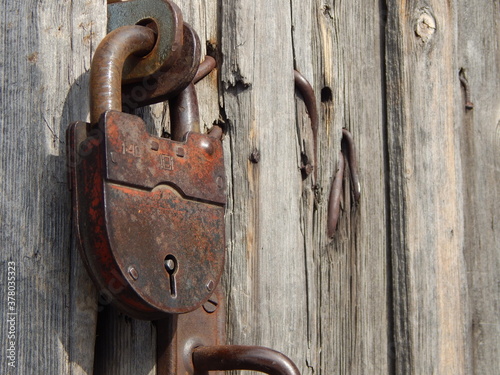 An old closed padlock hanging on the background of a wooden door. Closed barn, storeroom © vitd
