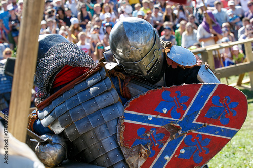 Medieval restorers fight with swords in armor at a knightly tournament photo