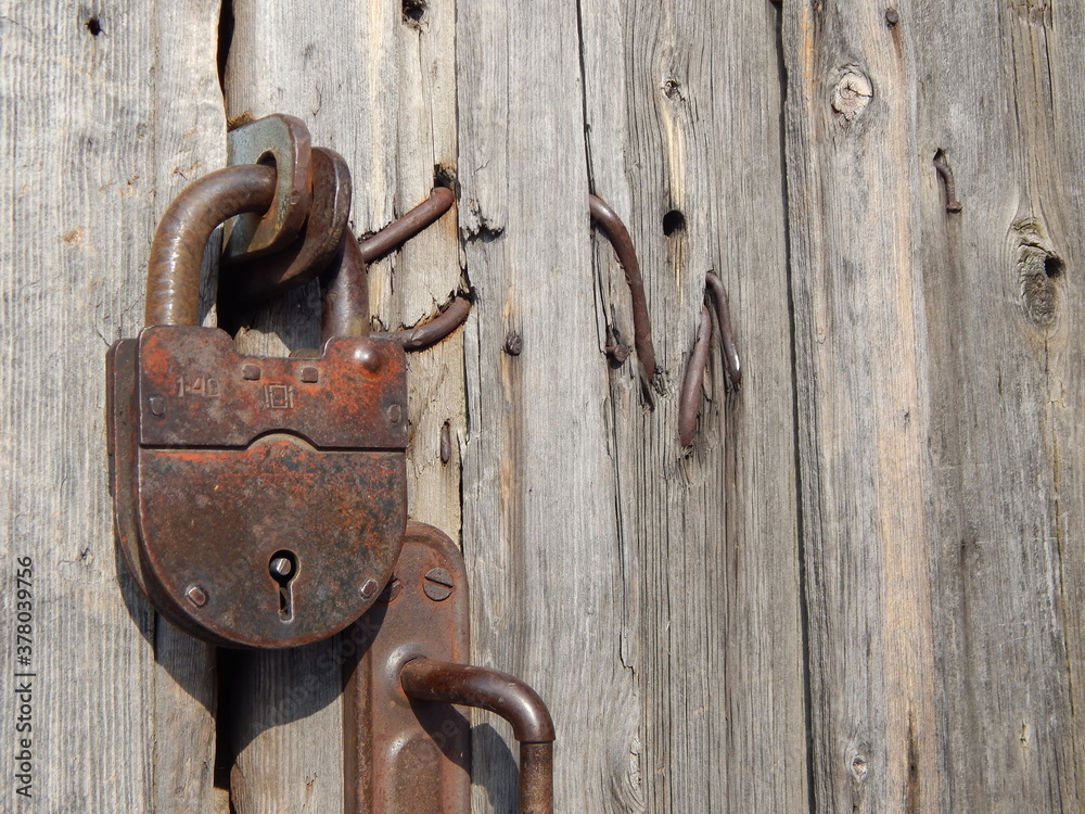 Old rusty padlock on the background of a wooden door. An old, rusty lock. Old rusty padlock on the background of a wooden door. An old, rusty lock.