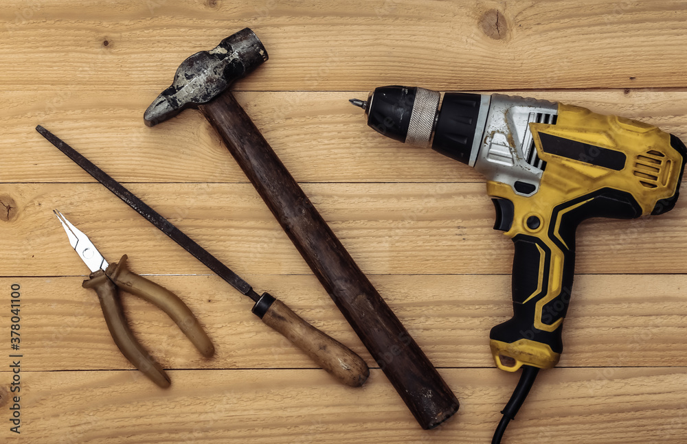 Old drill screwdriver and protective helmet, work tool on a wooden background. Top view Old drill screwdriver and protective helmet, work tool on a wooden background. Top view