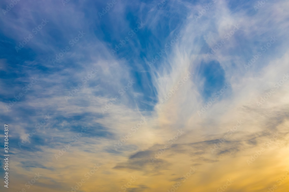 Abstract atmospheric background. Colored clouds in the evening sky. The sun sets in the evening and illuminates the clouds with orange light.