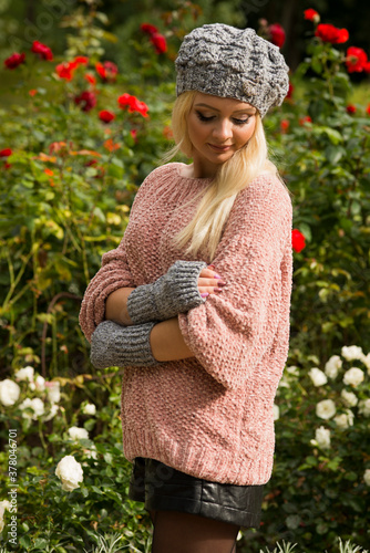 Girl in pink knitted sweater posing in the park
