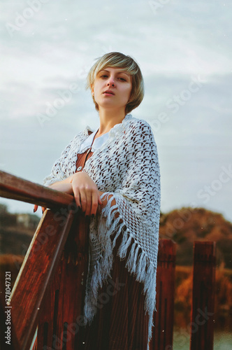 Lonely sad girl on a cold autumn day stands on the river bank photo