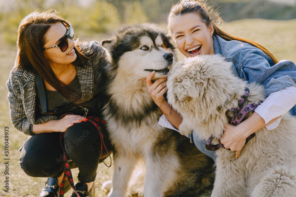 Obraz premium Women in a spring forest. Girls with cute dogs. Stylish friends walks.