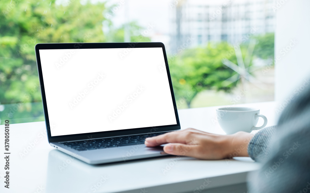 Mockup image of a hand using and touching on laptop touchpad with blank white desktop screen in office Mockup image of a hand using and touching on laptop touchpad with blank white desktop screen in office